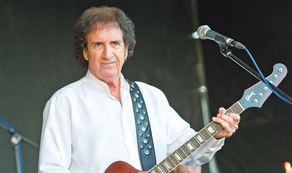 Tony Crane on stage playing the guitar. 
